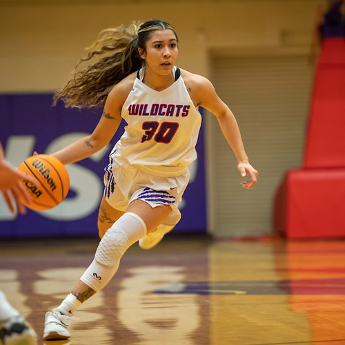 Linfield women's basketball player dribbling on the court.