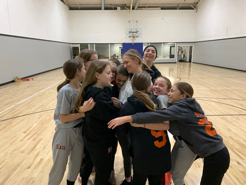 Alana Nuttman in a group hug with her student athletes