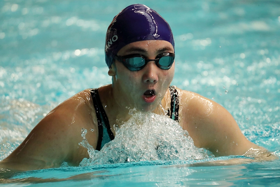 Ella emerges from the pool to take a breath while swimming the breast stroke.