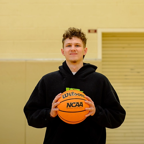 Kris posing with a basketball in front of a basketball hoop.