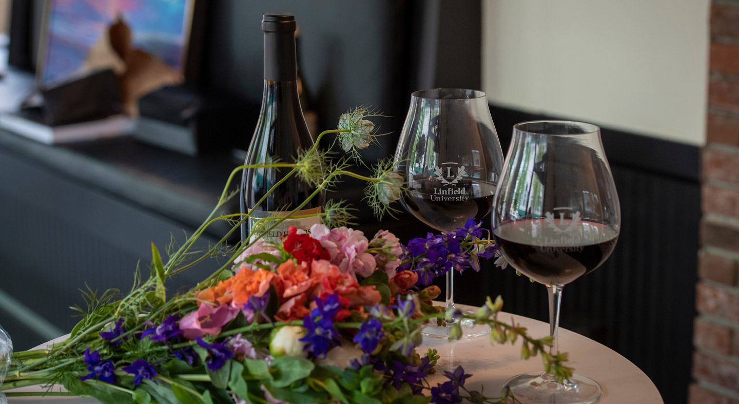 A bottle of red wine next to two wine glasses on top of a table in Acorn to Oak.