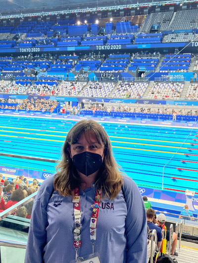 Stacey standing in the bleachers at the 202 Tokyo Games with the Olympic swimming pool in the background