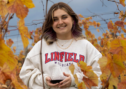 Emma Libby '23 in a vineyard holding a glass or red wine