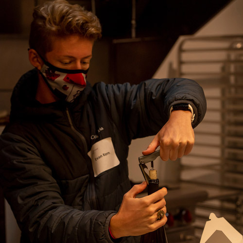 Evan Kern '23 opening a bottle of wine during a wine tasting