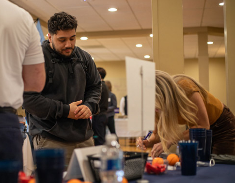 Male student visiting at an employer table at the career development job fair.