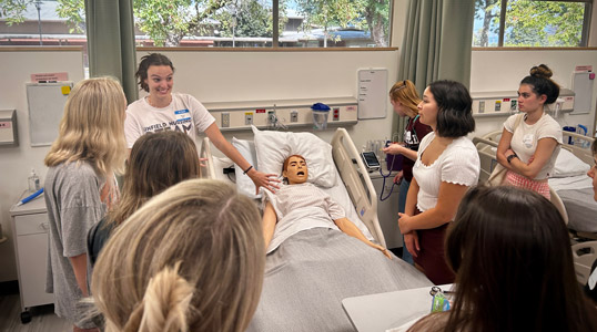 Nursing students with instructor and mannequin.