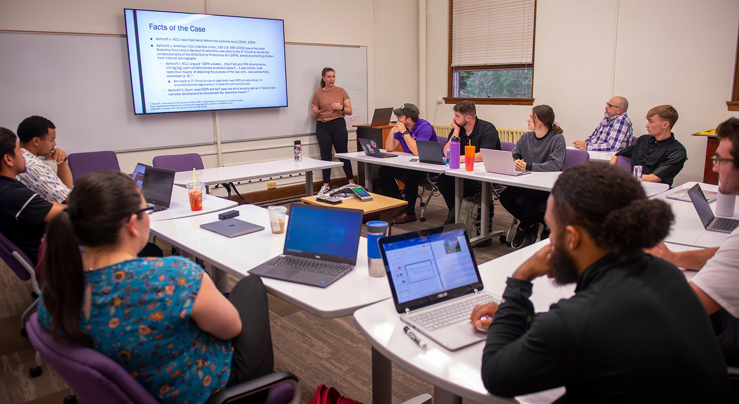 graduate students in the classroom listening to a student presentation