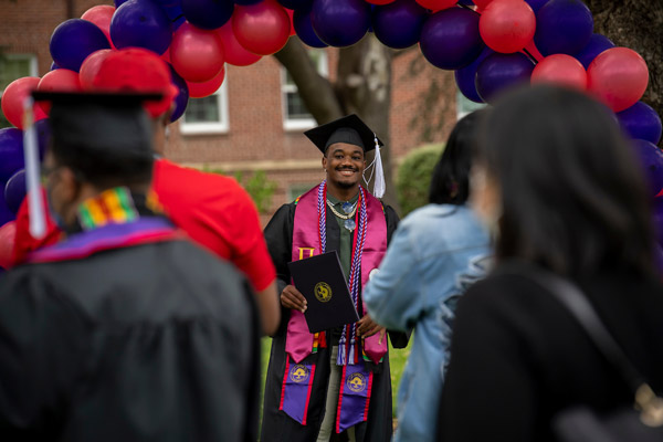 Ray-Ray smiling in his gap and gown receiving his bachelor's degree at Linfield Commencement in May 2021