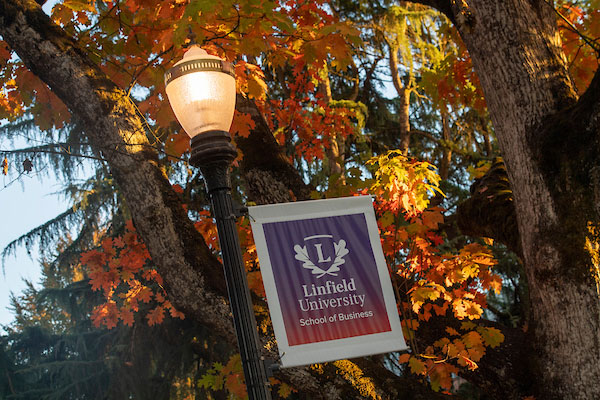 a light post with a Linfield University School of Business banner on the McMinnville campus in the fall