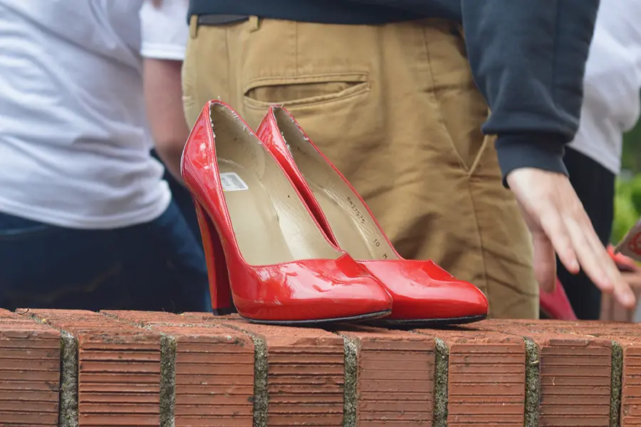 a pair of red heels on a brick wall.