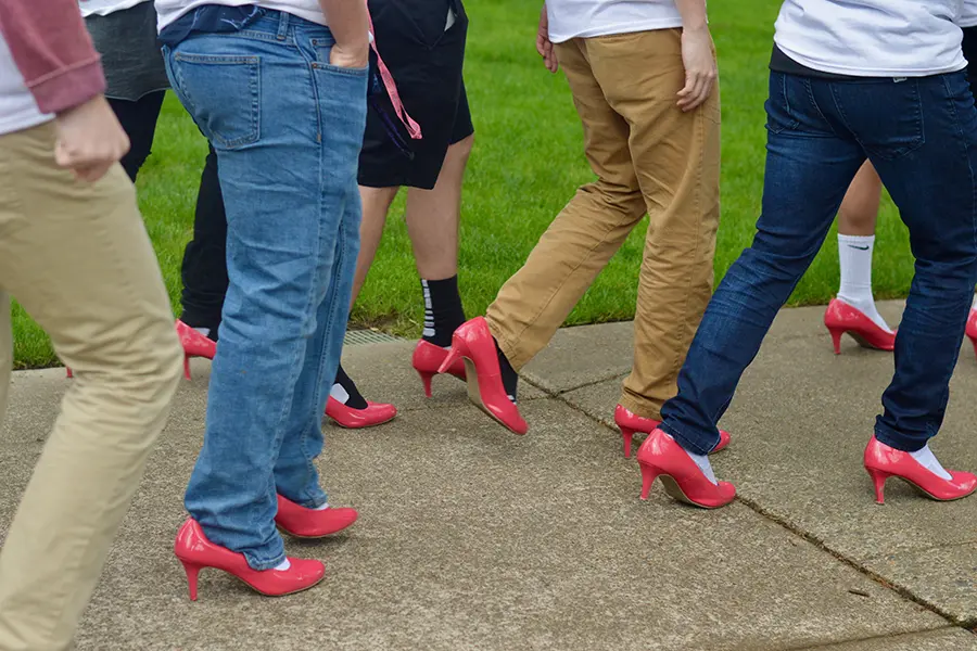 Member of Pi Kappa Alpha walking around the Linfield quad in high heels.