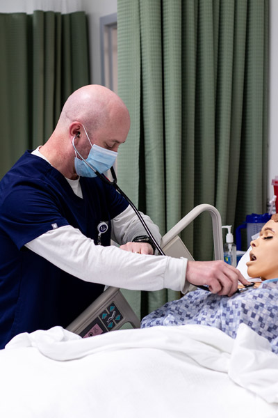 Zach Diamond '22 using a stethoscope on a manikin in a simulation lab