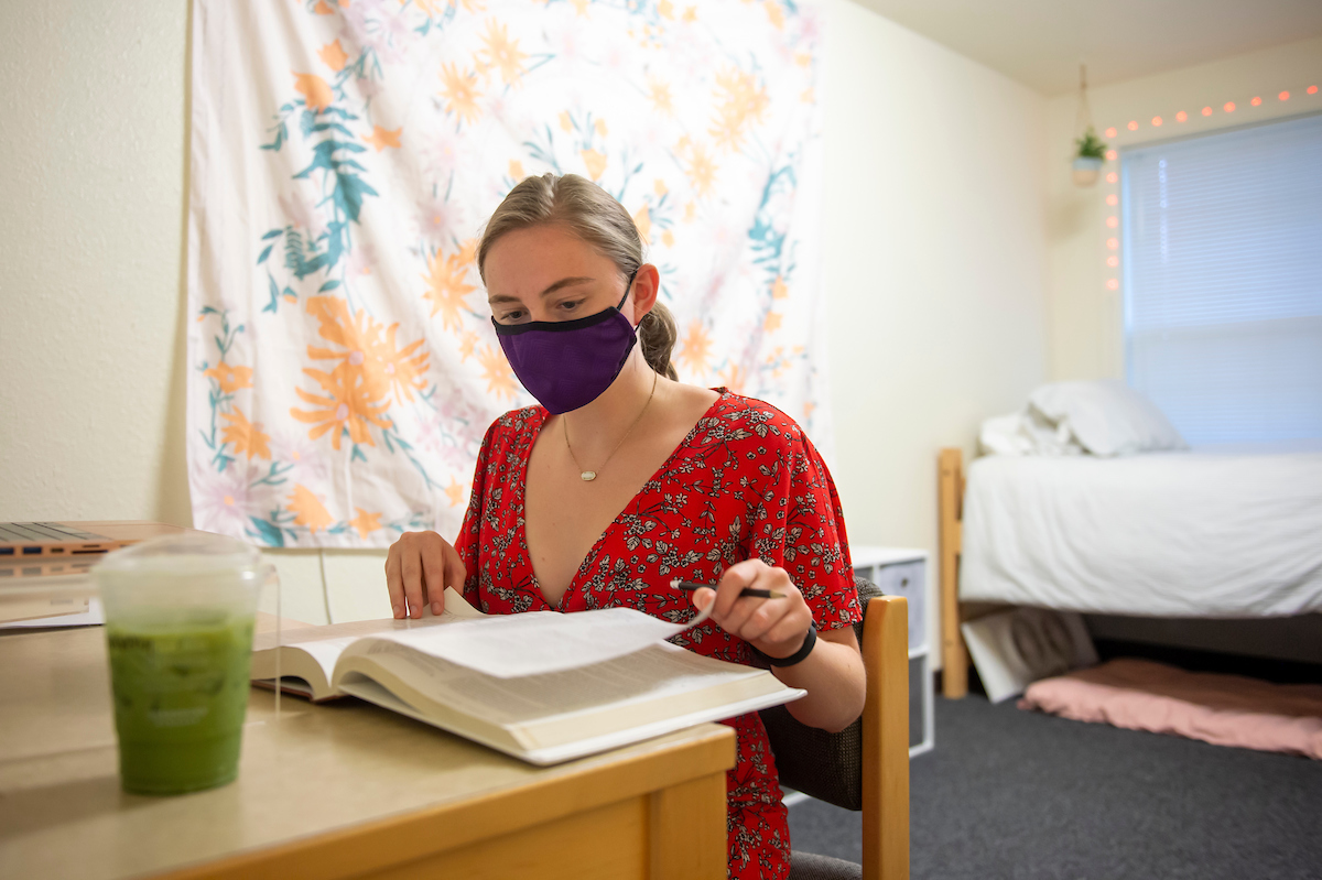 Student in dorm room studying in a mask