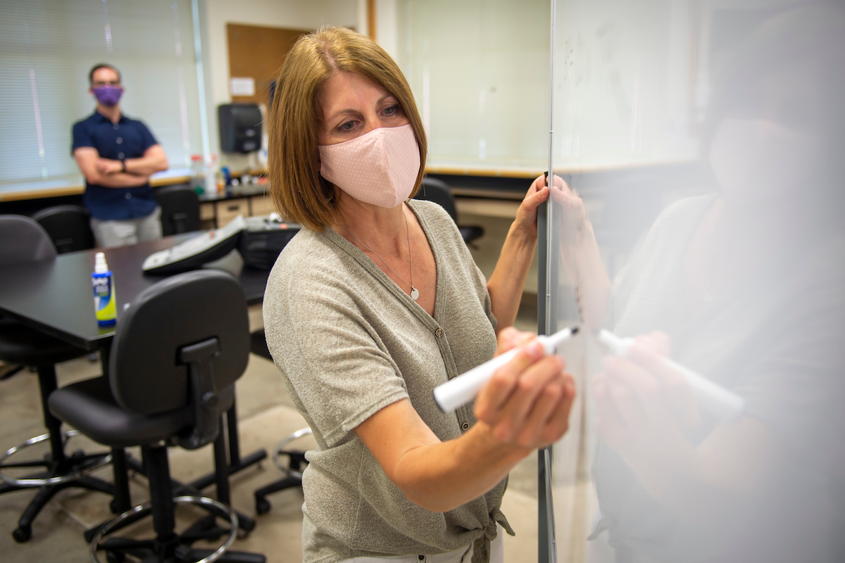 Associate professor Sarah Coste writes on a white board
