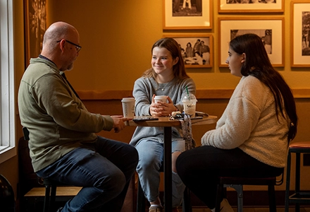 Chris Dahlvig talks to two students at Starbucks