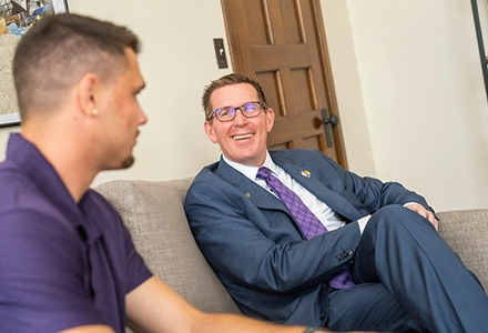 Mark Blegen sits on couch and talks to a student