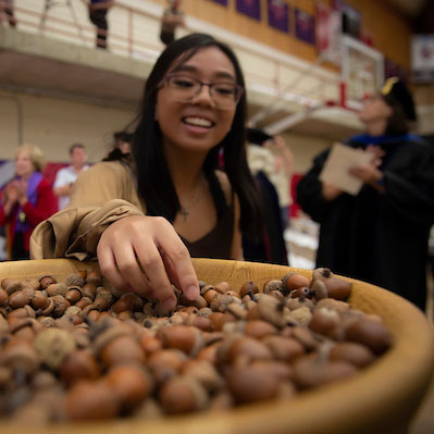 female student grabbing an acorn during Convocation