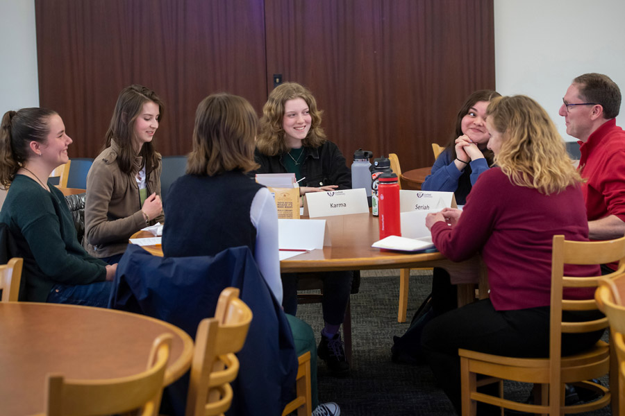 Four students around a table with the two leaders of the career development team.