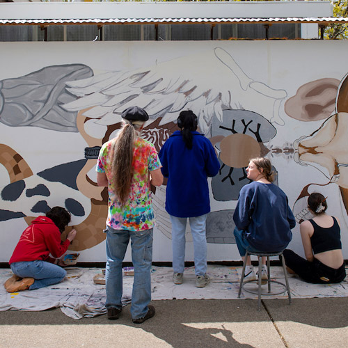 Students painting a mural on the building with Professor Shriver