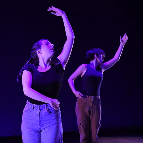 two students dancing on a dimly lit stage