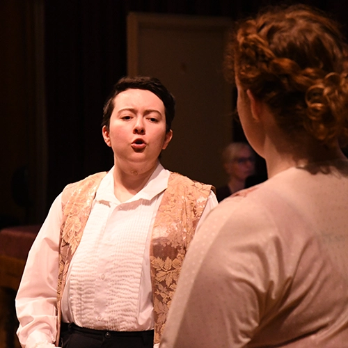 two students performing a song on stage.