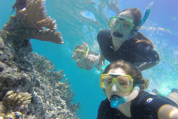 Three female students snorkeling the Great Barrier Reef in Australia