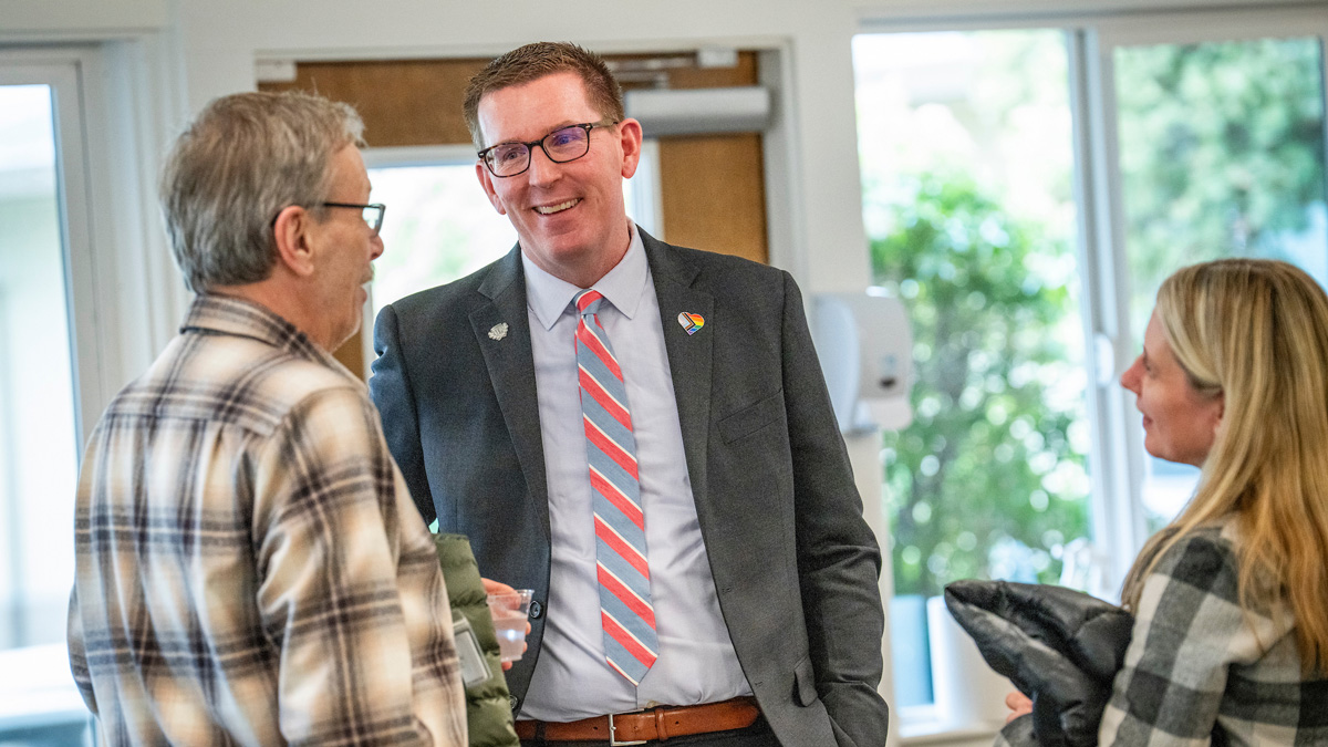 Mark Blegen laughs and talks to two people at an event