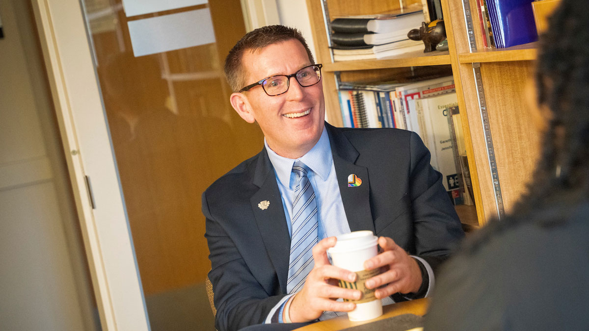 Portrait of President Blegen talking with others at a table.