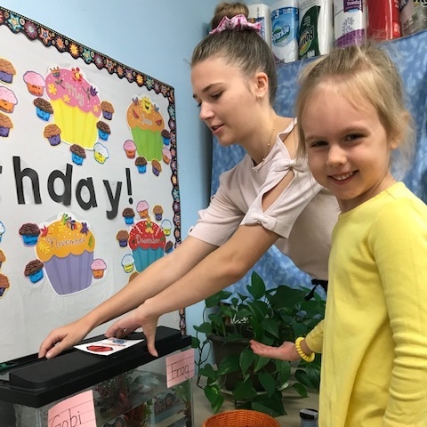 preschooler feeding fish with student teacher