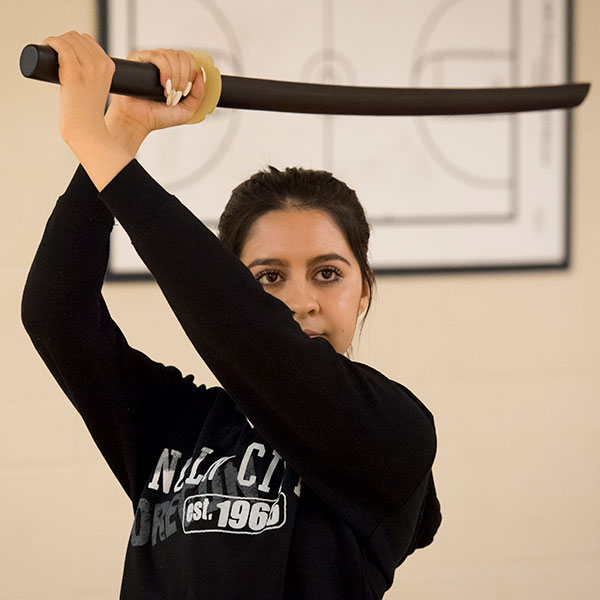 female student holding training sword overhead in Professor Ilundain's Philosophy of Mind course 