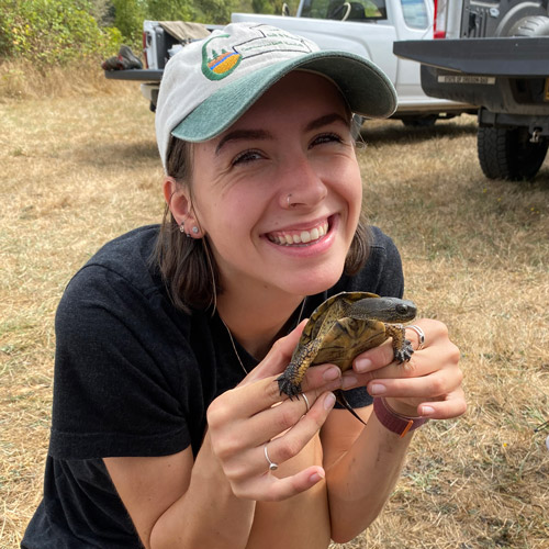 Linfield student holding a turtle during an environmental studies research project outing.