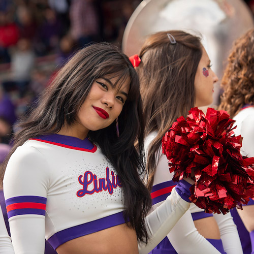 Kayley Dombrigues holding a pom-pom with the Linfield Dance Team at a football game