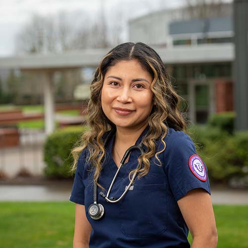 Nursing student in scrubs with stethoscope around her neck.