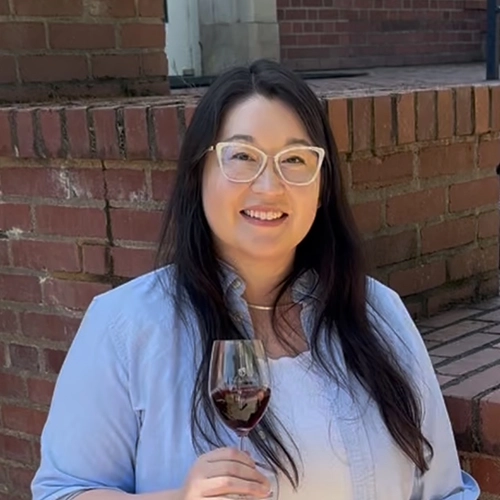 Female student smiling and holding a glass of red wine.