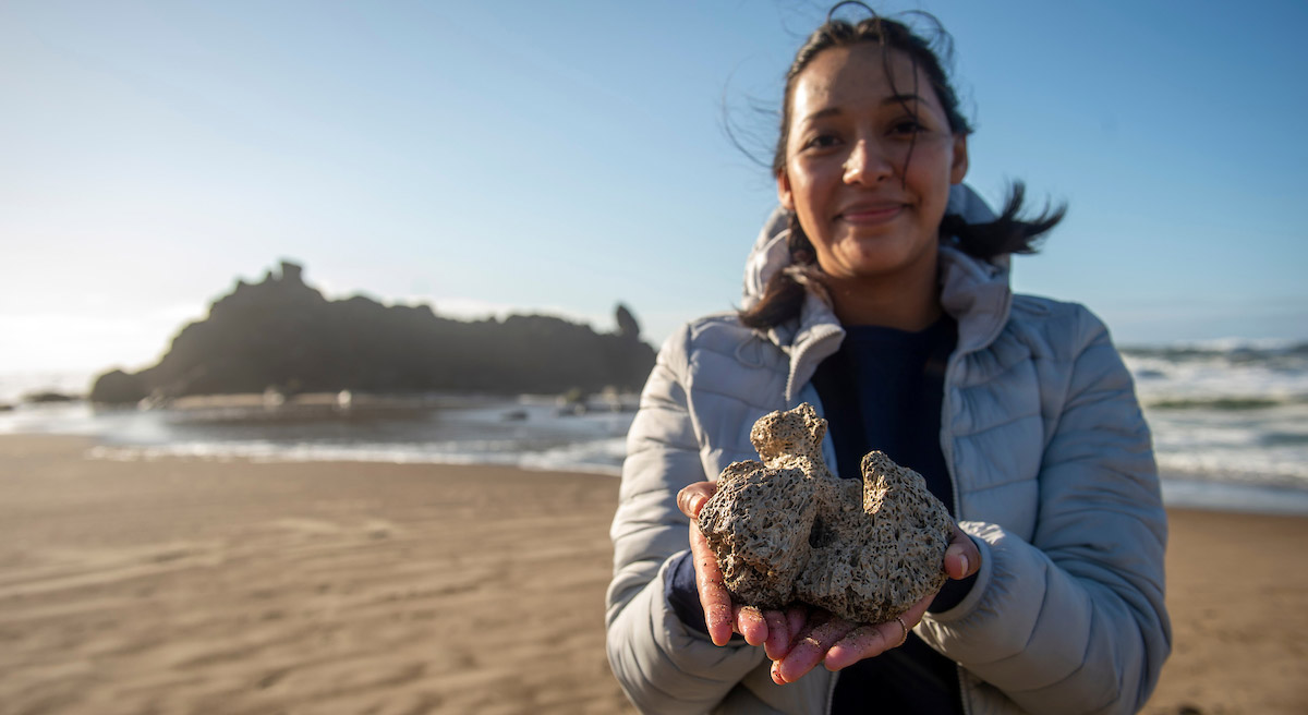female biology student holding a rock formation discovered on the beach