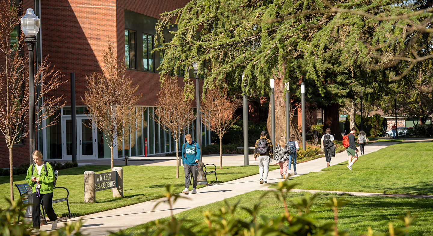Students walking along the path outside of the science complex in between classes on a sunny spring day.