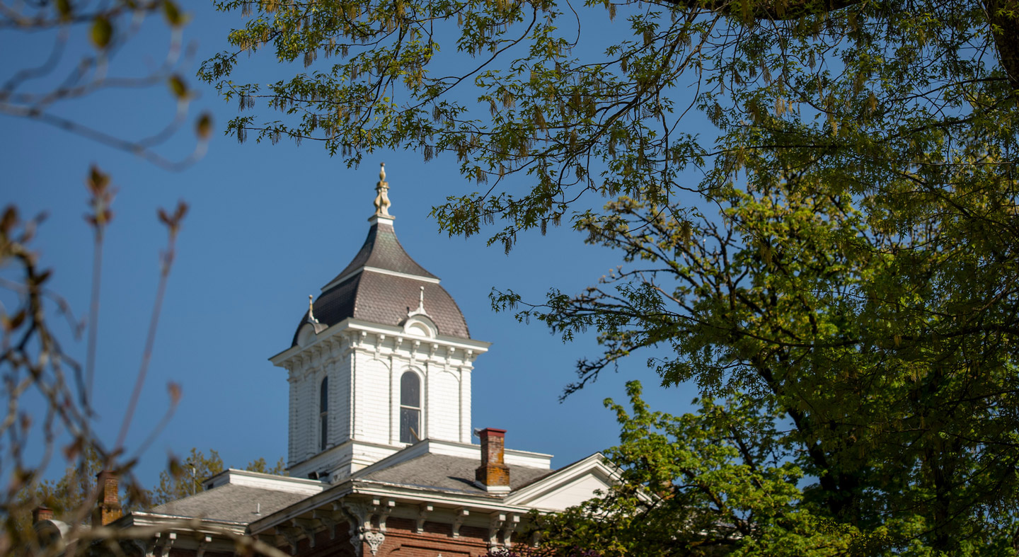 The top of Pioneer Hall through the trees.