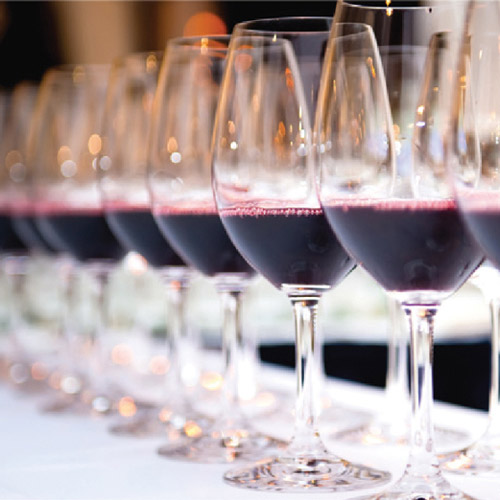 a row of wine glasses with red wine