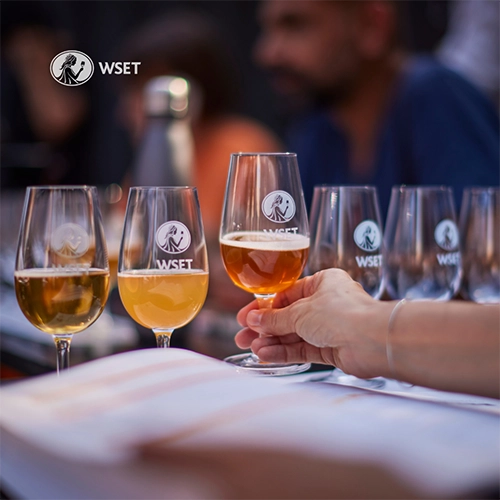 a hand grabbing a tasting glass filled with beer.