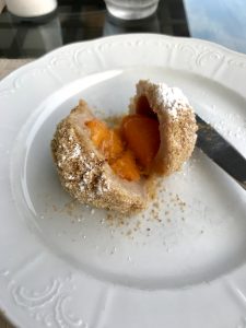 a cut open Austrian dumpling filled with an apricot on a plate