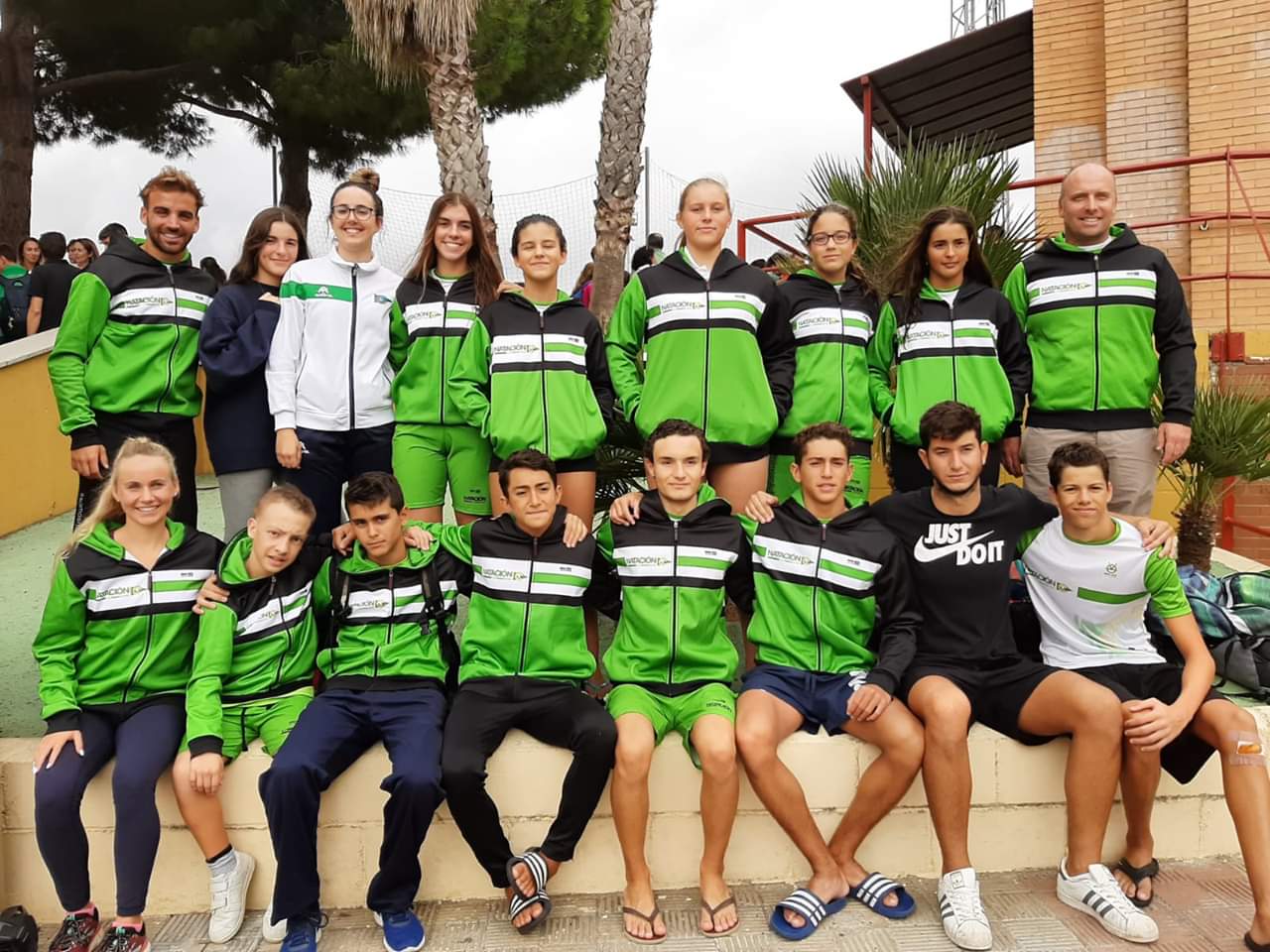 A group of people pose for a photo in green swim-team jackets