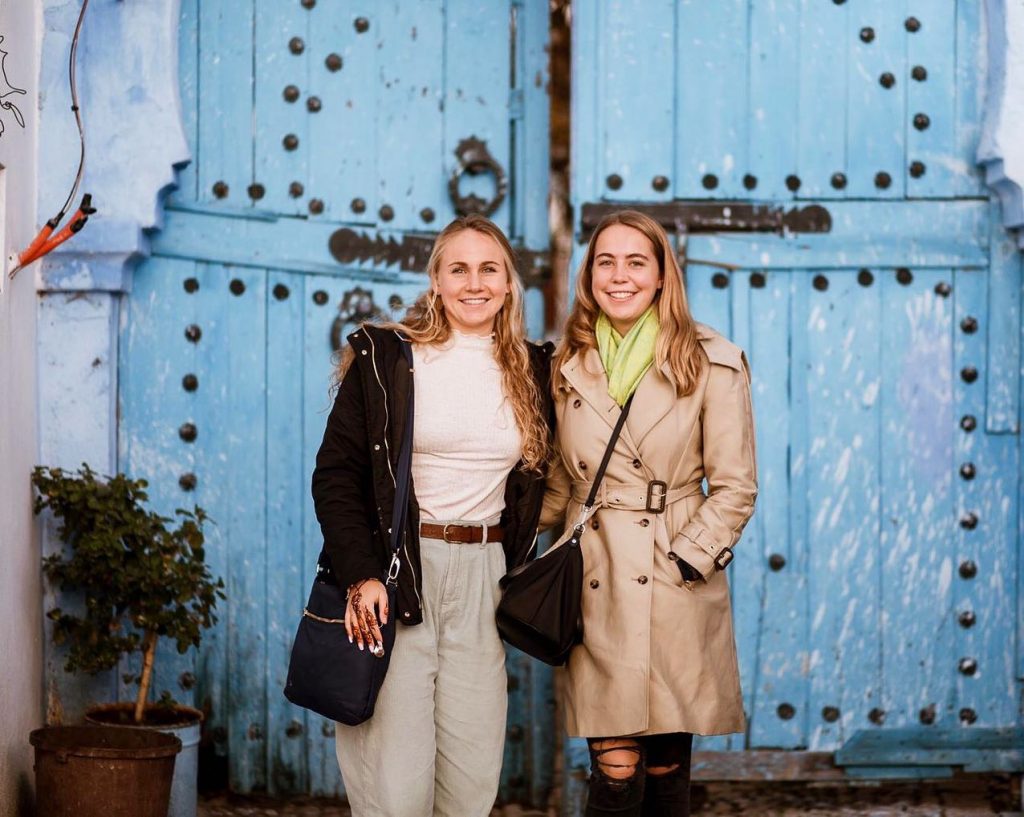 Morocco; 2 students in front of huge wooden gates.