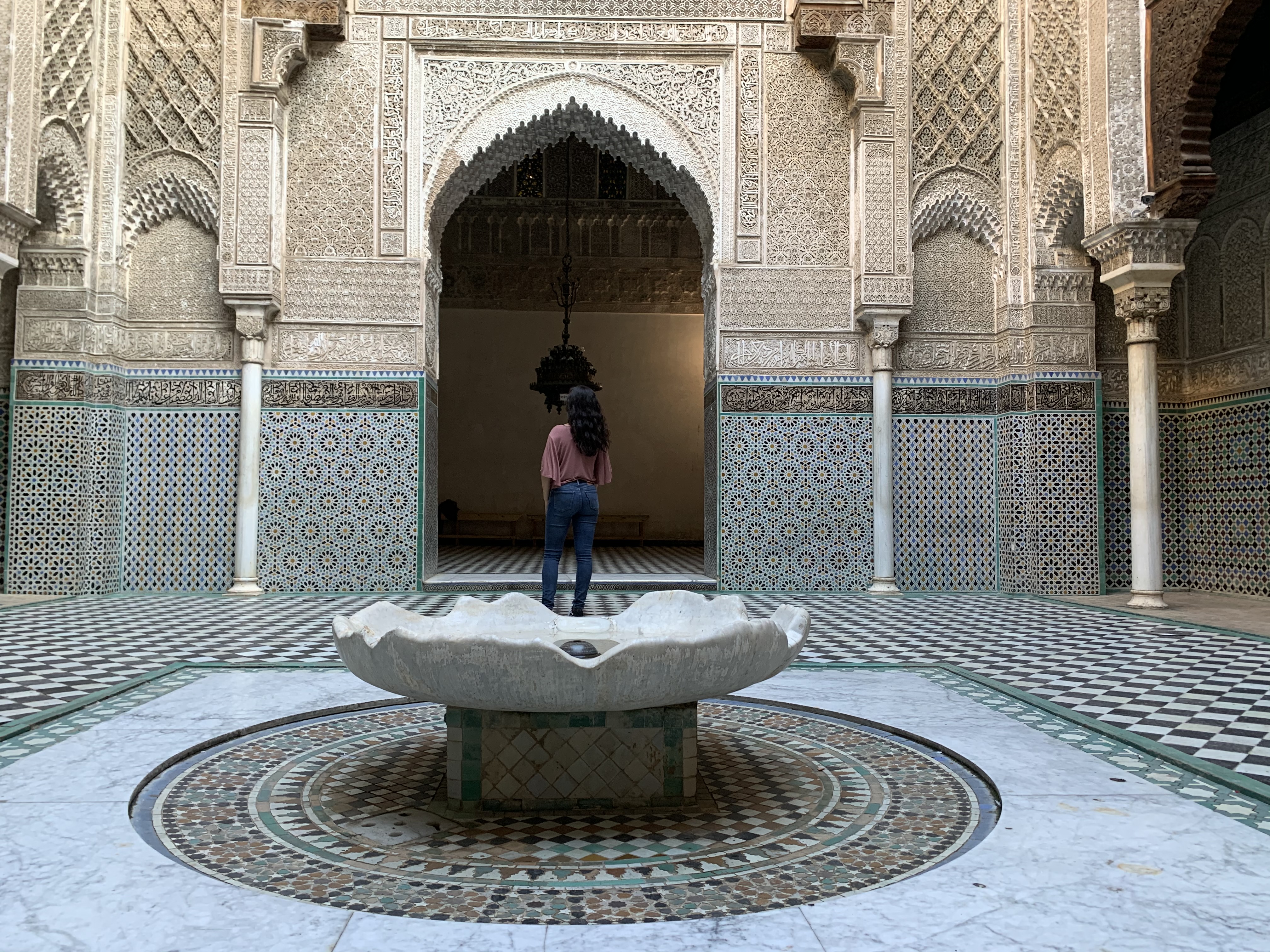 Student in the Al-Attarine Madrasa with a fountain in front.