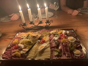 Meat and cheese plate on a table in front of four candles
