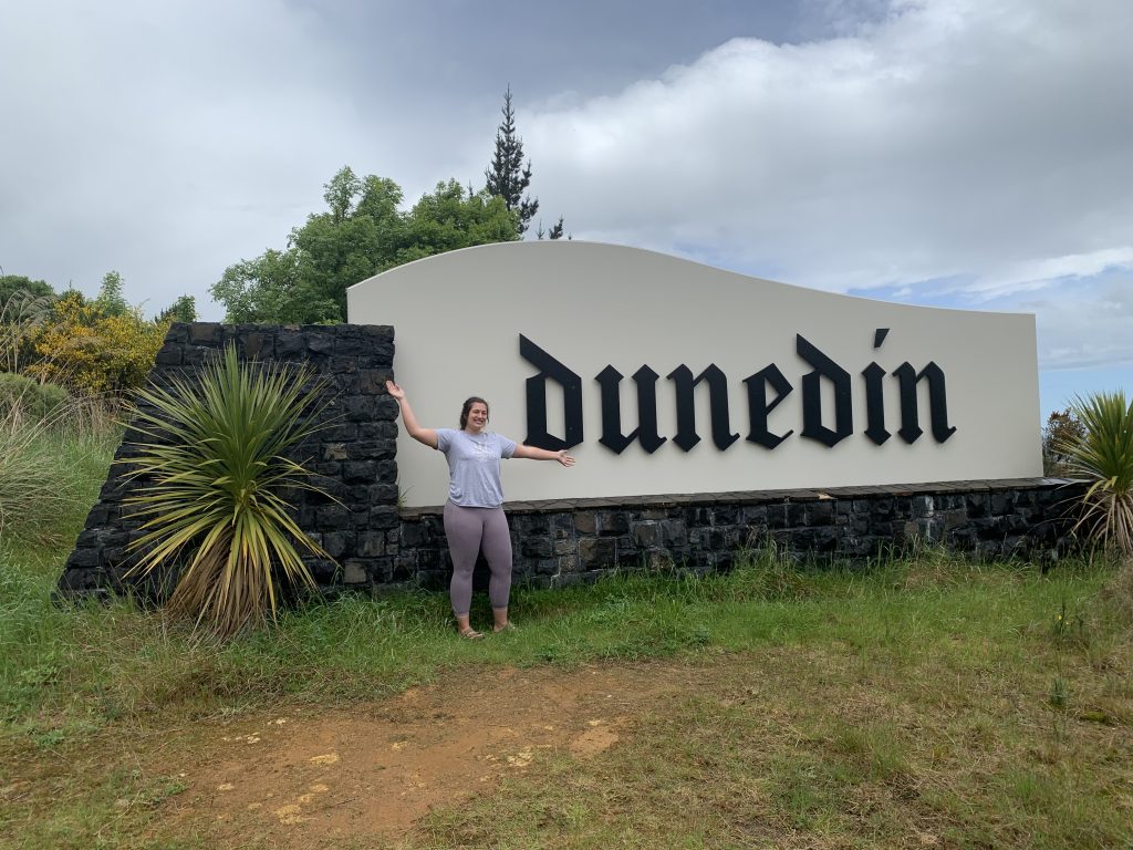 Author posing in front of the Dunedin city sign.