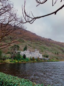 Kylemore Abbey with a hill in the background overlooking a lake.