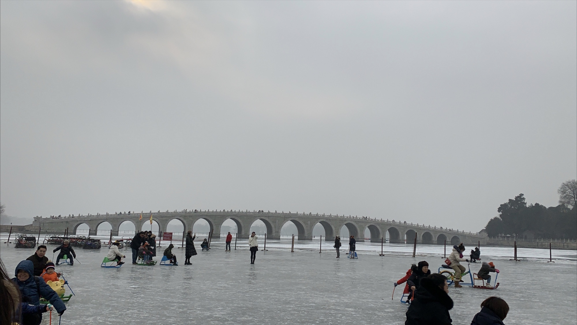 A bridge leading over the frozen lake to Summer palace. Ice skaters in the foreground