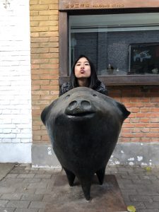 student standing behind a pig statue in 798