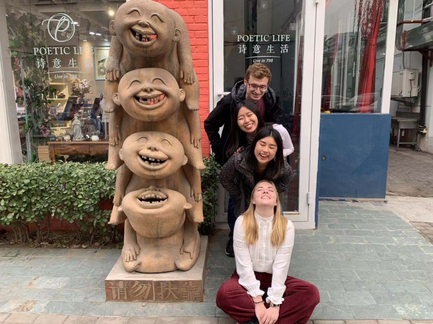 4 students posing with a sculpture of faces.