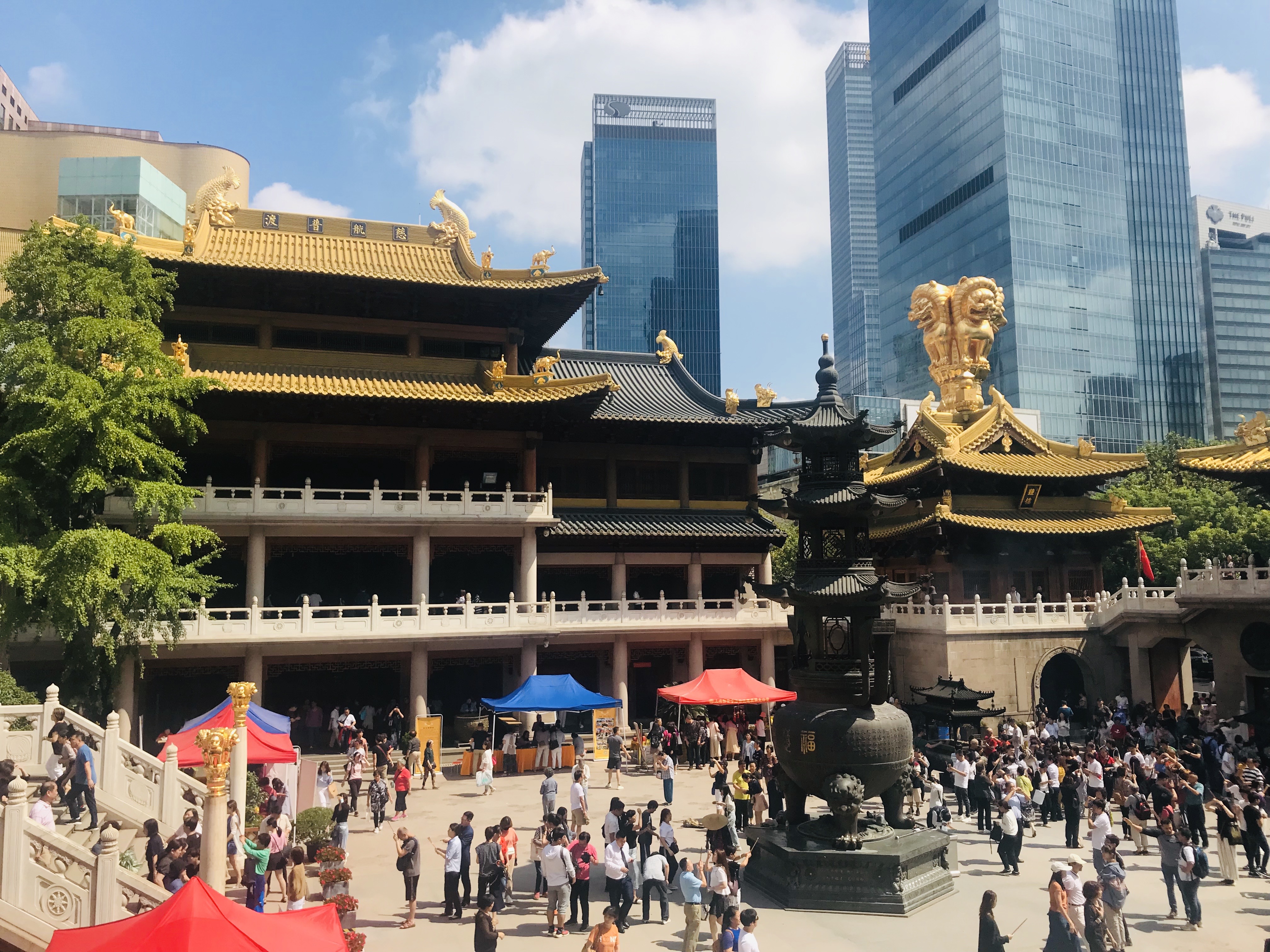 Jing'an Temple with the courtyard in the front and view of Shanghai skyscapers on the horizon.